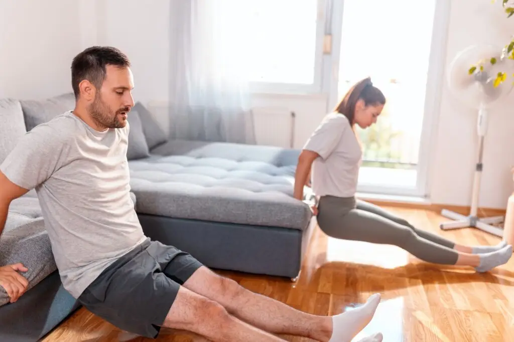 Couple doing triceps dips while working out at home