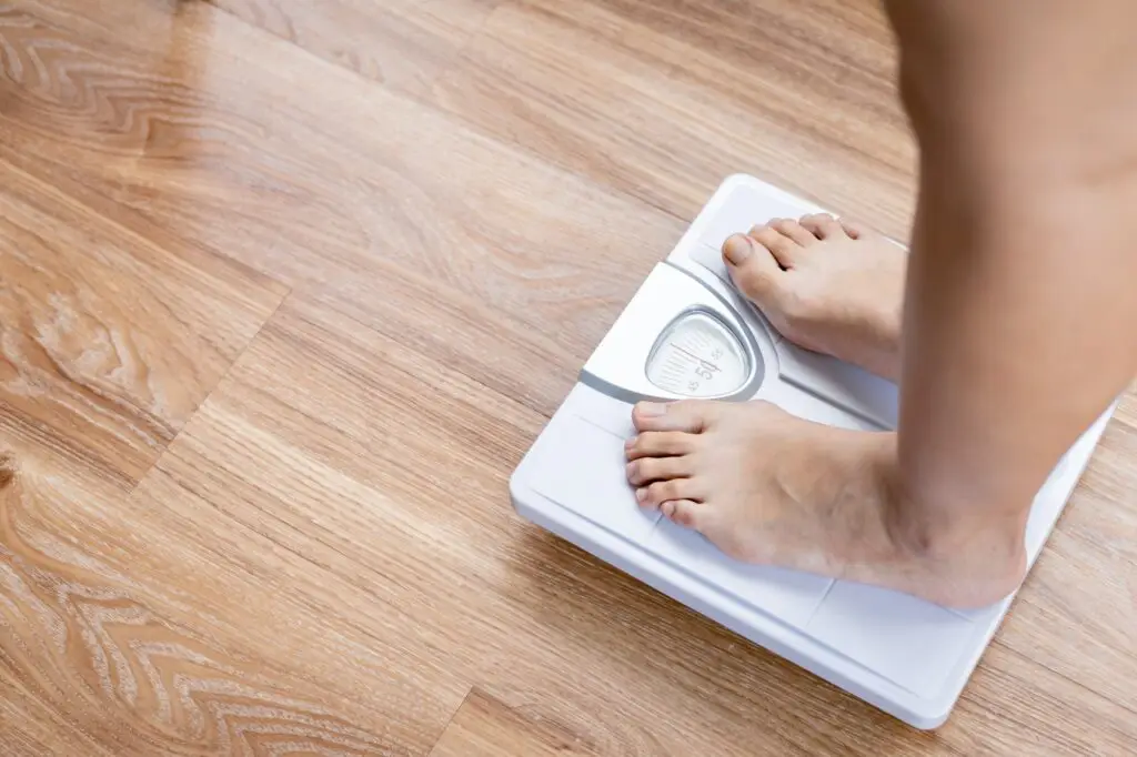 Female bare feet standing with a scales.