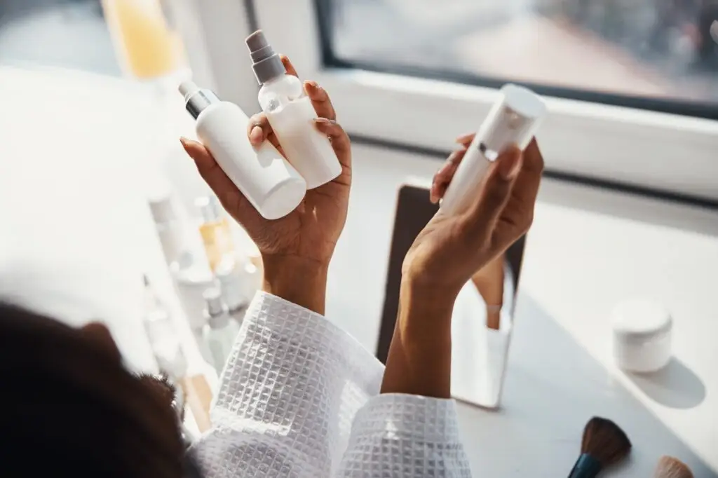 Female hands holding bottles of cosmetic cream and lotion